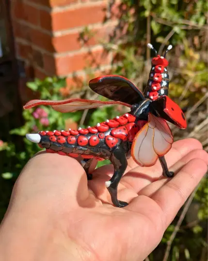 Une dragonne coccinelle rouge à point noir sur une main