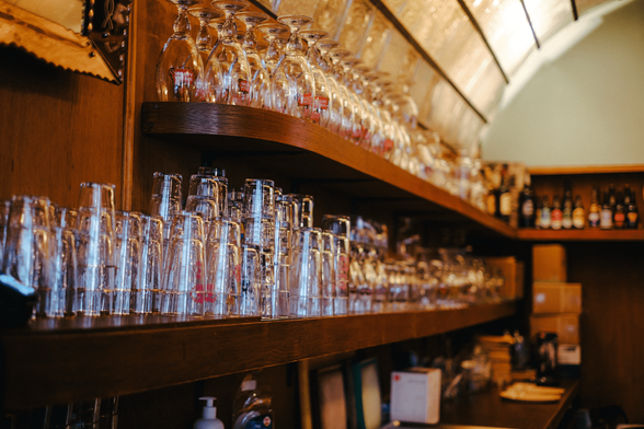 Glasses on shelves, a bit of the backlit, translucent, vaulted ceiling visible above it