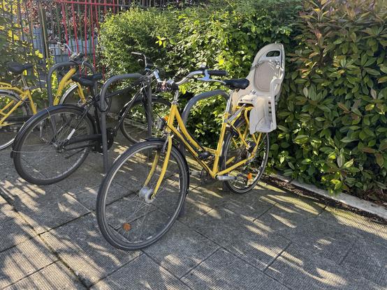 Photo d’un vélo jaune avec siège bébé à l’arrière.