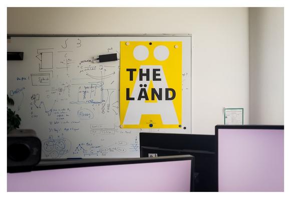 Ein knallgelbes "THE LÄND" Poster im bayrischen Büro.