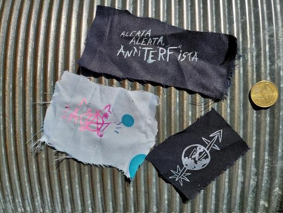 Three small patches. One reads 'ACAT', one reads Alerta, Alerta AntiTERFista, and the third one has a syndicalist Trans* Squatting symbol printed on it.