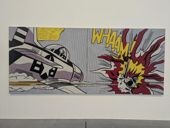 Photo of artwork "wham" by Roy Lichtenstein.  The artwork is taken from a comic and enlarged to fit a canvas.  Shows a plane shooting another plane.  Makes war seem fun and poppy.