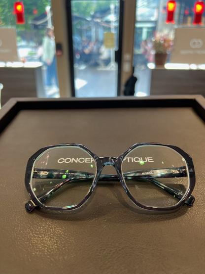 Paire de lunettes bleues et violettes sur un présentoir de chez l'opticien