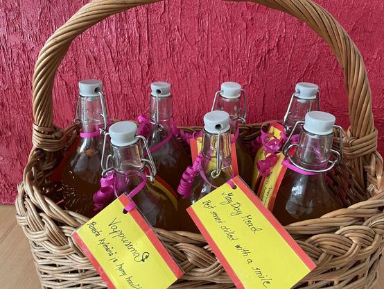 Kori täynnä simapulloja. Etiketissä tekstit:Vappusimaa! Parasta kylmänä ja hymy huulilla. May Day Mead. Best served chilled, with a smile.