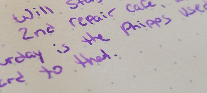 Writing sample on iroful paper. Purple letters on slightly off white page.