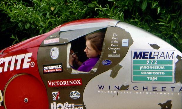 A rider peers out of the side of a fully faired Windcheetah recumbent tricycle