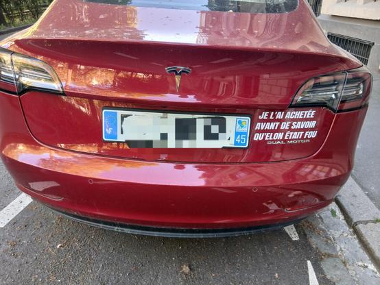 Une Tesla rouge vue de derrière, immatriculation floutée

Sur la droite des lettres blanches collées sur la voiture disent "je l'ai achetée avant de savoir qu'Elon était fou"
