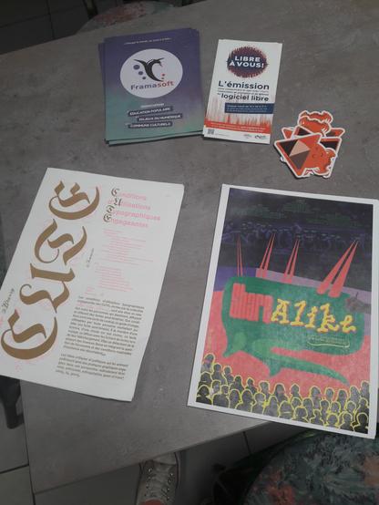 Table avec de la propagande de framasoft et l'april, la CUTE de Bye bye binary et des affiches de Share alike.
