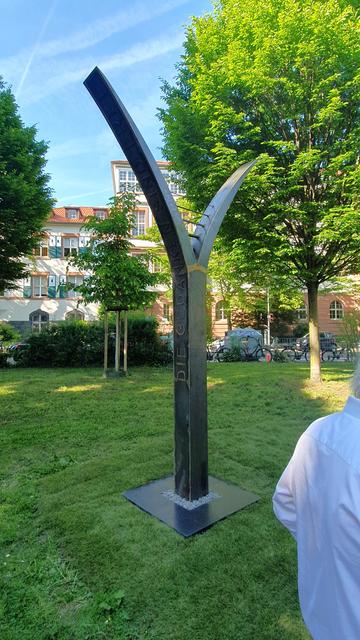 Eine ca. 4m hohe Stahlskulptur, die aussieht wie ein Y. In der Gabelung sind vier Querstreben angebracht, die aussehen, als wären es Saiten von einem Musikinstrument. Auf der linken langen Seite des Y steht "Die Gedanken sid frei" auf der anderen Seite "Edelweißpiraten".
