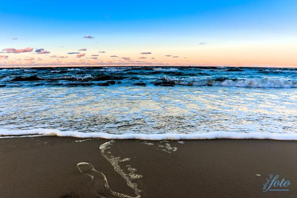 Ein herrlicher Sandstrand im Vordergrund, leichte Schaumkrone und dahinter Ostsee satt mit einem pastellfarbenen Sonnenuntergang 😍
