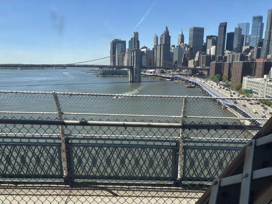 View of the river separating Manhattan from Brooklyn, from the Q train. A bridge is seen.