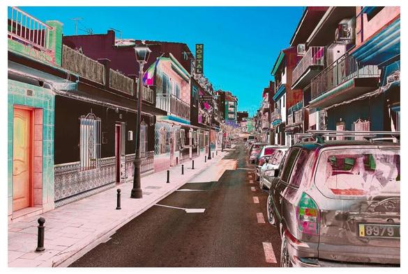 Colour modified photograph showing a suburban street in Spain.  Cars are parked to the right, while on the left there are lantern (los faroles) streetlamps.  Further down the street on the left is the Hostal Los Faroles.