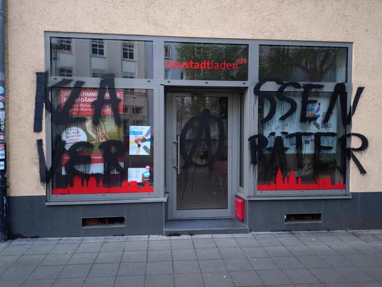 Ladenfront der SPD Neustadt, mit einem Schriftzug in schwarzer Farbe und einem Anarchie-Logo großflächig beschmiert