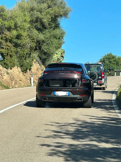 Porsche Macan with partly opened trunk.. in front is a small off-road car