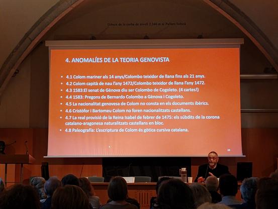 caption de la diapositiva: 4. Anomalíes de la teoria genovista.
4.1 Colom mariner als 14 anys/ Colombo teixidor de llana fins als 21 anys
4.2 Colom capità de nau l'any 1472/Colombo teixidor de llana l'any 1472
4.3 1583: el senat de Gènova diu ser Colombo de Cogoleto. (4 cartes!)
4.4 1583: pregons de Fernando Colombo a Gènova i Cogoleto
4.5 La nacionalitat genovesa de Colom no consta en els documents ibèrics
4.6 Cristòfor i Bartomeu Colom no foren nacionalitzats castellans
4.7 la real provisió de la reina Isabel de febrer de 1475: els súbdits de la corona catalano-aragonesa naturalitzats castellans en bloc
4.8 paleografia: l'escriptura de Colom és gòtica cursiva catalana

Francesc Albardaner explicant la diapositiva sobre Colom
