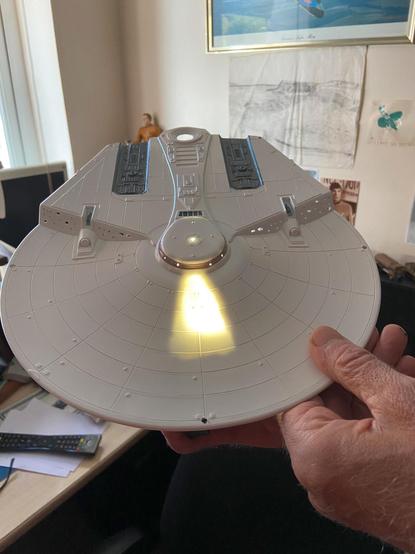 A unfinished photo of the top section of a Miranda-class starship. A light underneath it shows how the windows and registration lights might look like on the finished model.