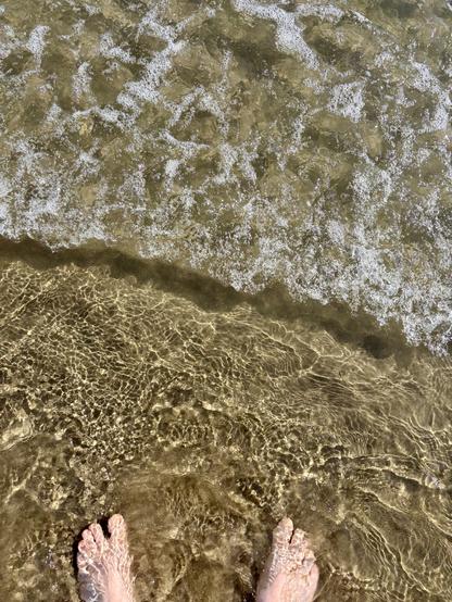Dipping my toes into the sea as a small wave breaks