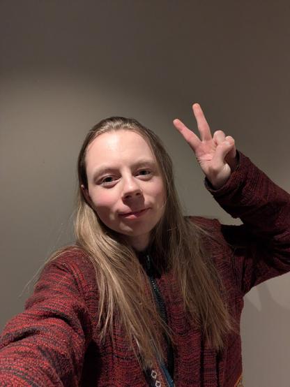 In the cold, unfeeling void, a lone woman captures their own selfie, within a barren room in his apartment.

The subject, appearing to be in their early twenties, stands before a plain wall, their face illuminated by the light.

A red textured jacket is draped upon them, a mute testament to their fleeting existence.