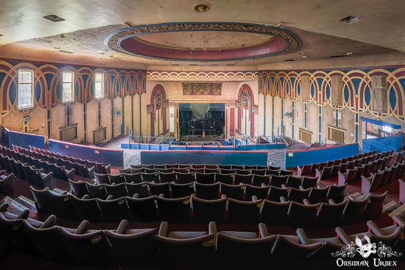 Art deco cinema. Burgandy, navy and gold accents on geometric shapes of circles and arches on the walls. Seats are red velvet