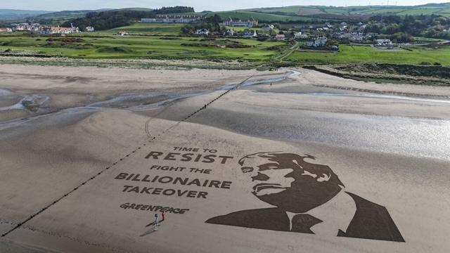 A giant sand painting on the beach next to Trump's golf course says Time to resist. Fight the Billionaire takeover. - Greenpeace with a likeness of Donald Trump.