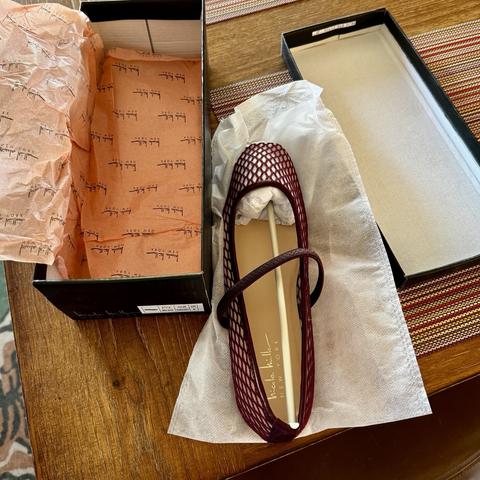iPhone photo of one burgundy mesh ballet flat sitting on crumpled tissue paper, in between an empty shoebox and a shoebox lid
