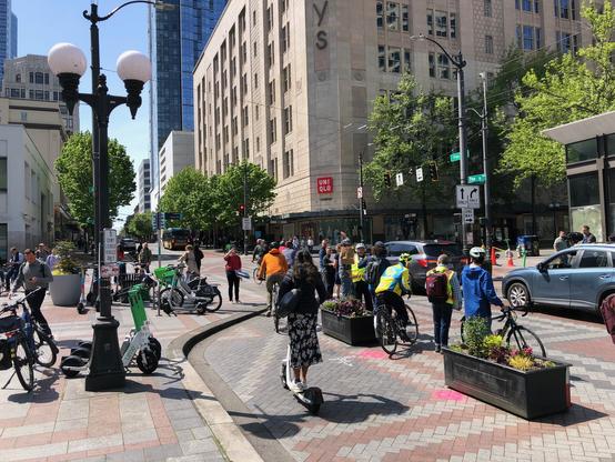 People on scooters and bike travel in the human-protected bike lane.