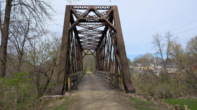 Dark brown Diverge bicycle leaning on the wooden railing of a steel truss railroad bridge which now carries the La Crosse River State Trail.