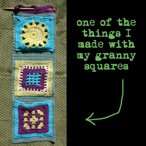 Long crochet strip of blue-grey yarn with 3 granny squares attached to it as pockets. The pockets are a combination of yellow, cyan, white, and purple. On top of the strip are 3 hole to attached it to a wall or hooks.