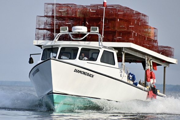 Dead rise workboat with red crab pots on top.