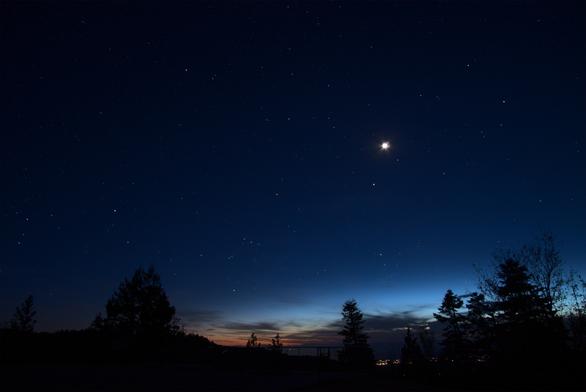 Evening twilight shows the bright stars of the winter constellations setting in the west. Two 'guests' are also in the frame...the moon (grossly overexposed), and Jupiter below it.

Cirrus clouds are moving in from the west, but only block the brightest parts of the twilight sky near the horizon.

The lights of La Luz shine at the bottom of the frame, right of center.