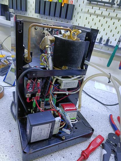Die Innereien einer Kaffeemaschine und um etliche Kabel ergänzt. Neben den original-Bauteilen Boiler, Pumpe und Timer-Steuerung sieht man ein Solid-State-Relais, einen Mikrocontroller und ein Netzteil.