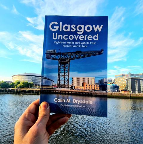A book about Glasgow held up against the Glaagow skyline.