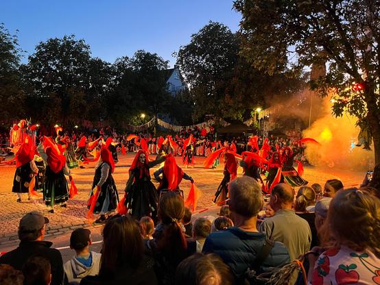 Im Kreis tanzende Hexen, ältere in rot/schwarzen Kleidern