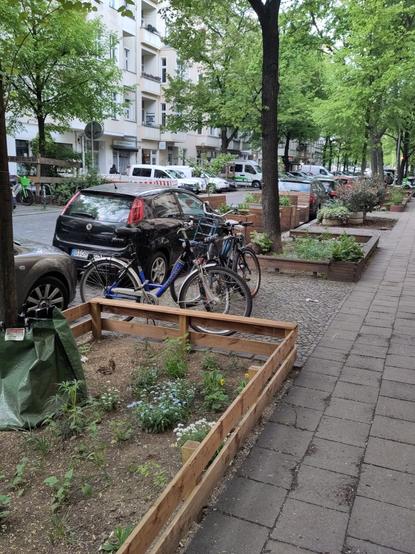 Niederbarnimstraße in Berlin-Friedrichshain am 22.04.2025 mit von Nachbarn bepflanzten Baumscheiben und einer Sitzecke auf der Fahrbahn, die ca. 2 PKW-Stellplätze einnimmt.