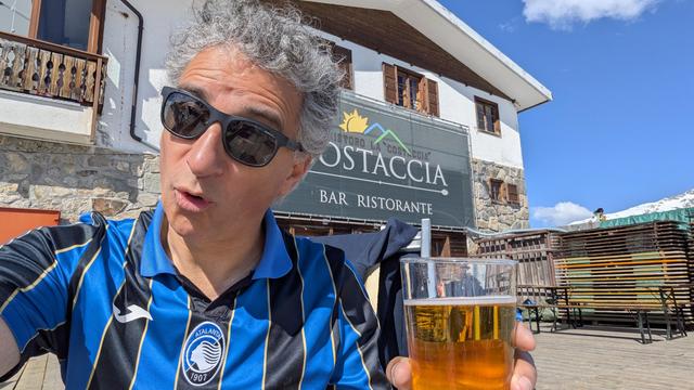La foto rappresenta una persona con gli occhiali da sole, la maglietta dell'Atalanta con una birra in mano all'aperto, fuori da un rifugio a Livigno