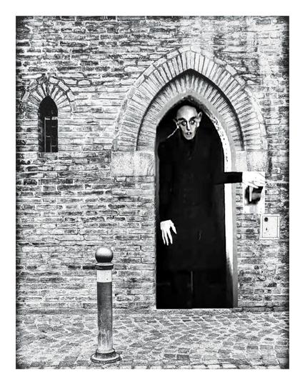 The same scene as previous. This time there is a tall, pale faced man (Count Orlock from Nosferatu) standing in the doorway with his hand on a light switch.