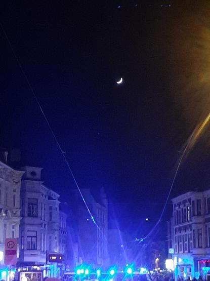 photo take at the take back the night demonstration in bremen
the protesters are out of frame, at the bottom edge of the image there are the blue lights of police cars, high above the old buildings in the background a waxing crescent moon is visible in the night sky