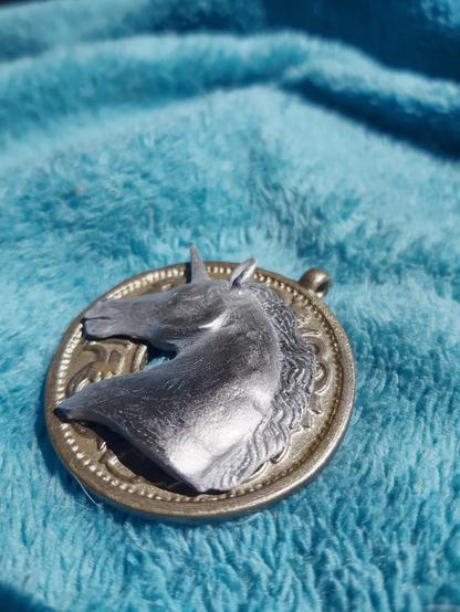 Un pendentif doré orné d'une tête de licorne argentée.