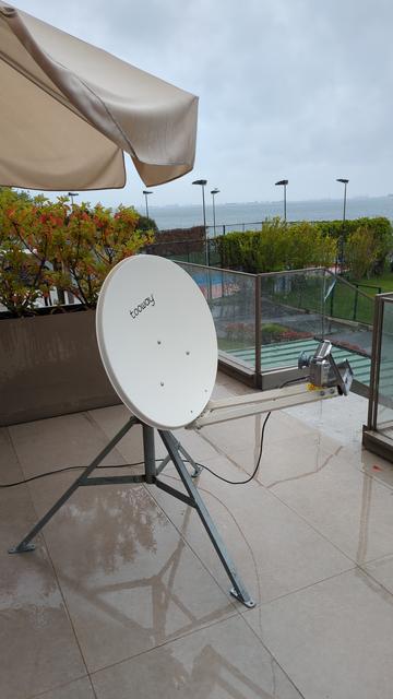Rainy weather. In the distance there is sea. On a wet hotel balcony a tooway satellite dish