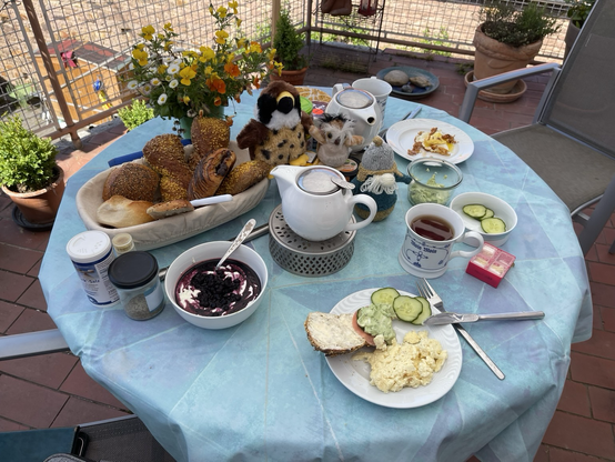 Gedeckter runder Frühstückstisch mit Brötchen, Rührei, Quark und den Plüschies Hedi, Chaplin und Waldhild