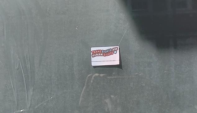 A sticker in support of trans people on a window
