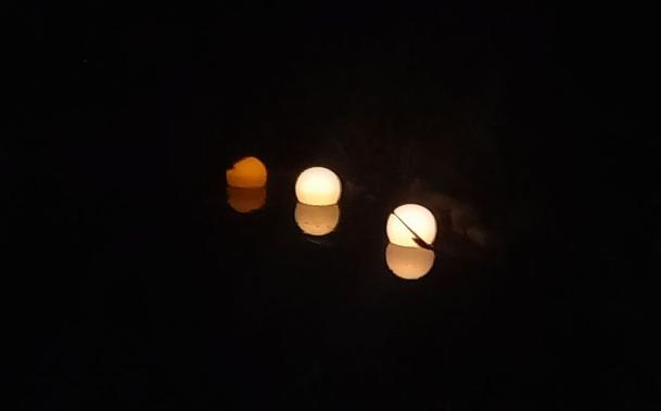 Three floating lights on a pond at night
