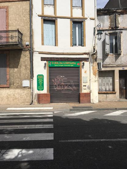A Moissac, la devanture close d'une épicerie proposant (quand y'a pas le rideau de fer) des spécialités lusitaniennes.