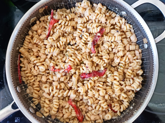 Die Pasta mit Bohnen und 
Chili-Stücken in einer großen Pfanne.