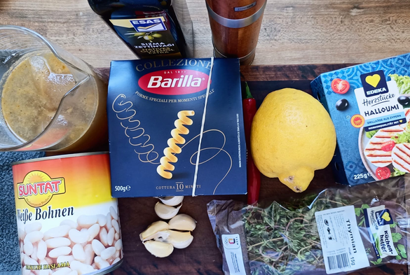 Eine Dose weiße Bohen, eine Packung Barilla Fusili Ducati Corti n. 292, eine Packung Halloumi, eine sehr große Zitrone, 6 Zehen Knoblauch eine Packung frischer Thymian, ein Glaskrug mit Gemüsebrühe, Olivenöl und eine Pfeffermühle.