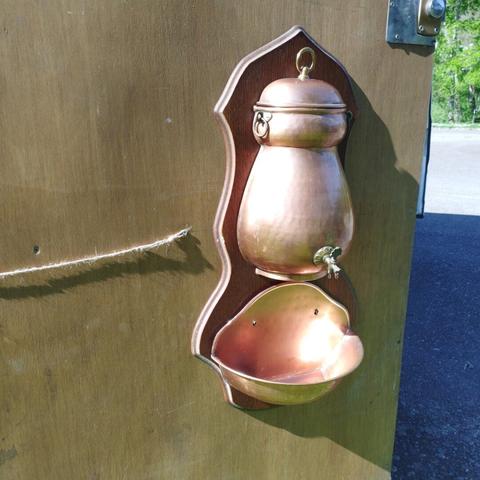 fontaine à eau en cuivre, sur son support en bois, fixée sur la face intérieure de la porte arrière droite du TawaMusi (le camtar). la lumière éclaire à partir de la gauche