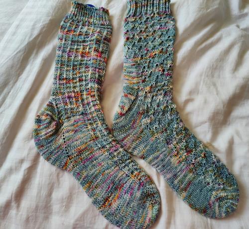 A pair of handknitted socks in a speckled blue yarn