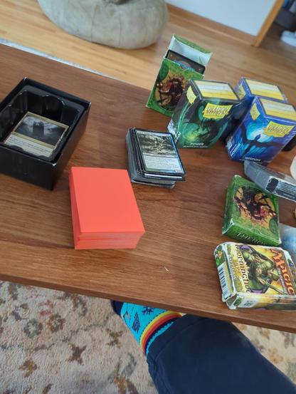 Several decks of Magic the Gathering cards and sleeves on a table.