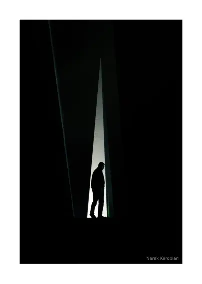 A silhouette of a man standing in front of a lit stele in the Armenian Genocide Memorial Complex in Yerevan