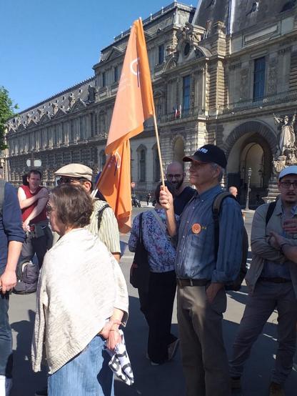 Photo de militants présents à l'hommage. Un d'entre eux tient un drapeau orange du RAAR.